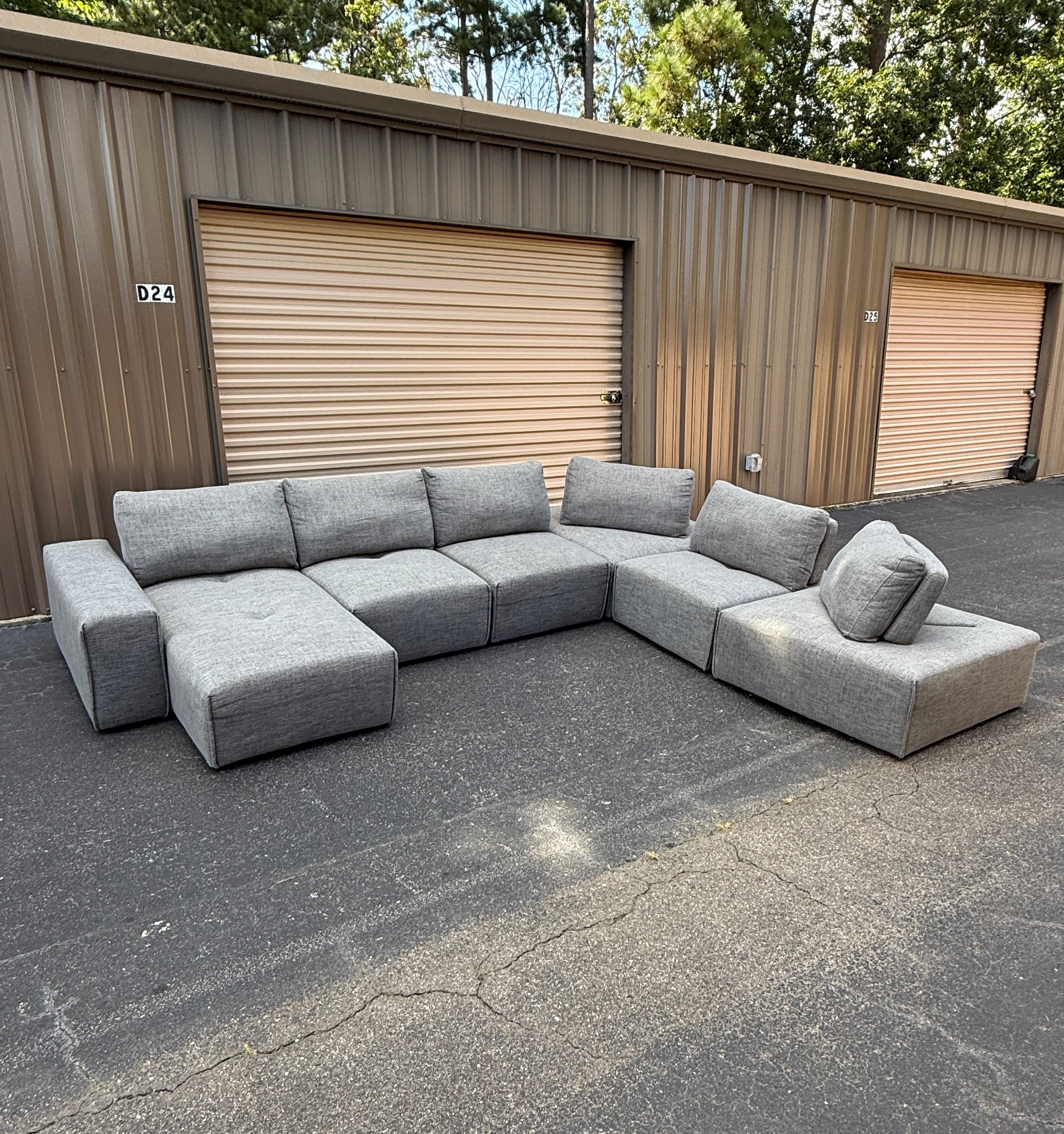 Gray sectional sofa in front of storage units with a clear sky.